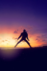 Silhouette of a man jump at sunset sky