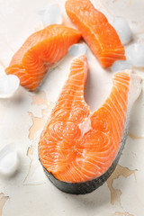 Fresh raw salmon and ice cubes on light background
