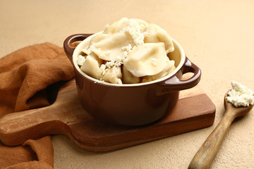 Pot with tasty dumplings on color background