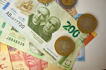 Mexican pesos bills spread randomly over a flat surface