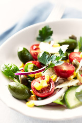Healthy salad with green olives, sweet corn, cherry tomatoes, red onion, baby spinach, capers and fresh herbs. Close up. 