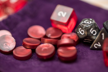 Role playing game dices and tokens lying on a purple bag where they are stored