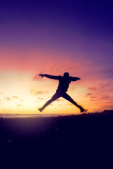 Silhouette of man jumping on beach at sunset