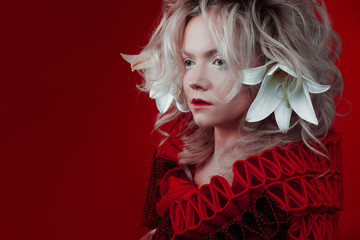 Shades of red. Attractive woman, in a red dress, posing on a red background, with white lily...