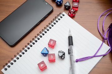 Set of pen, notebook, smart phone and dices to play role game like dungeons and dragons.