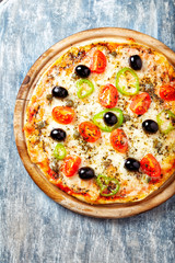 Pizza with cherry tomatoes, mozzarella cheese, jalapeno pepper, capers and black olives. Bright wooden background. Top view.