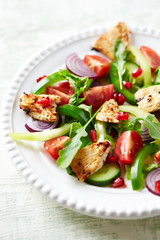 Healthy Salad with Pomegranate seeds, Chicken Briest, Green Pepper and fresh Basil. Bright wooden background.