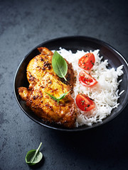 Spicy chicken with rice on black stone background. Close up.