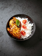 Spicy chicken with rice on black stone background. 