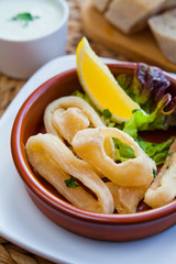Deep fried squid rings -  Spanish cuisine famous tapas -  calamari served on the fresh lettuce and lemon wedge.