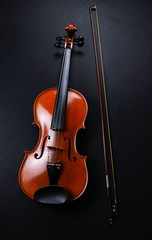 The wooden violin and bow put on black canvas background