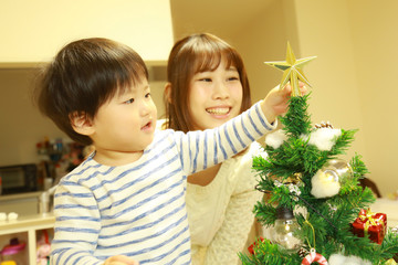 クリスマスツリーの飾りをつける親子