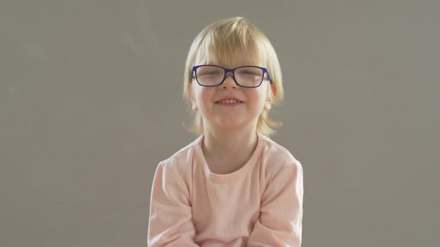 Portrait of funny blond child in new glasses. Boy puts on and adjusts glasses