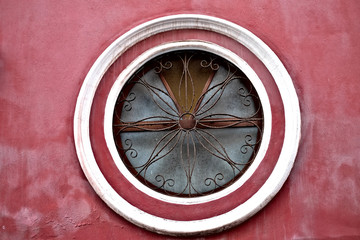 A big round window with a floral grill, architecture detail of an old church building.