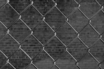 black and white closeup of chainlink fence with grunge urban background