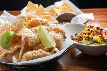 Pork Rinds also called chicharron or chicharrones, guacamole with diced fruits on top  and tortilla...