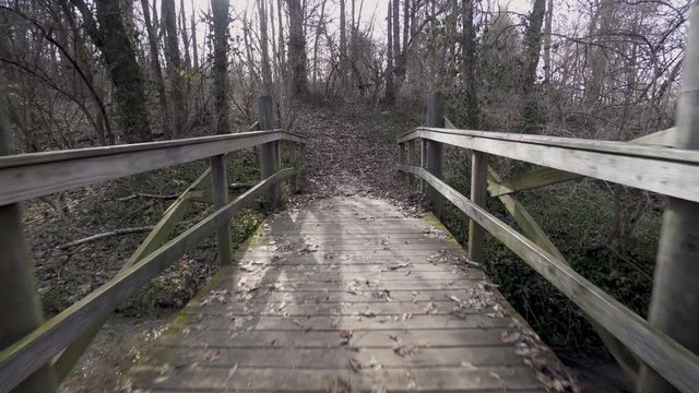 POV Crossing a Wooden Bridge on Foot in Wooded Park