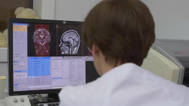 doctor examines an MRI image on a monitor