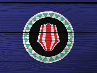 Bougainville flag color painted on Fiber cement sheet wall background. Red and white upe headdress superimposed on a green and white kapkap, on cobalt blue.