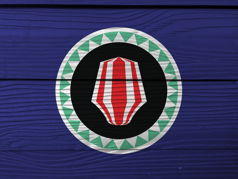 Bougainville flag color painted on Fiber cement sheet wall background. Red and white upe headdress superimposed on a green and white kapkap, on cobalt blue.