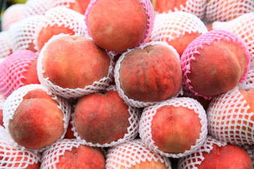 Lots of delicious looking very fresh peaches on sale at an outside market on a sunny Saturday.