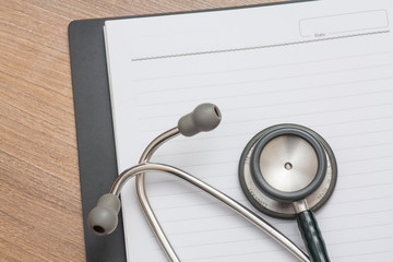 Medical concept : stethoscope on note book with wood background