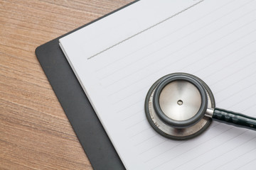 Medical concept : stethoscope on note book with wood background