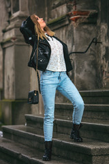 Urban style girl standing on steps in an old town looking up above her