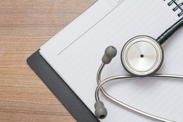 Medical concept : stethoscope on note book with wood background
