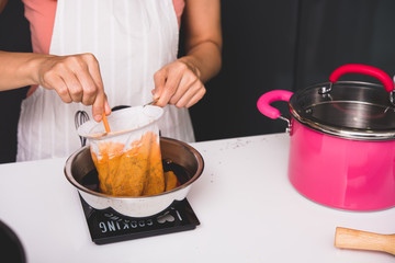 Woman girl in kitchen cooking pouring drip hot thai tea