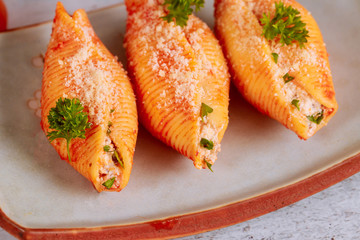 Pasta shells filled with ricotta, meat and parmesan on plate. Close up.