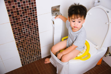 Asian little  kid 2-3 years old sitting on a kid bathroom accessory toilet