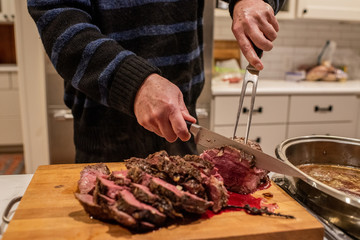 A chef cuts freshly cooked red meat