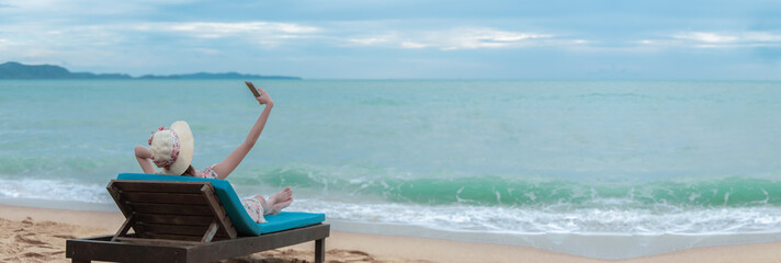 Happy travelling woman on the beach chair raised hands up with happiness, summer beach vacation...