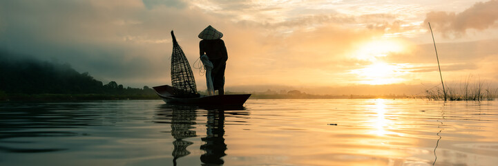 Fisherman throwing fishing net during sunrise.
