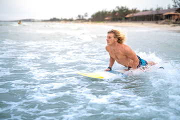 Blond caucasian surfer checking out the waves on a surf spot in Vietnam, Asia