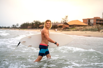 Fototapeta premium Blond caucasian surfer on a beach checking out the waves on a surf spot in Vietnam, Asia
