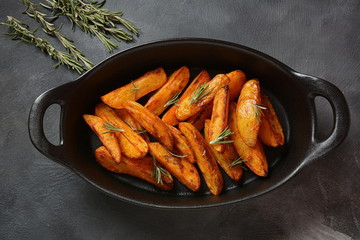 Baked, fried potato wedges with spices and rosemary. Roast potatoes with spices in the frying pan