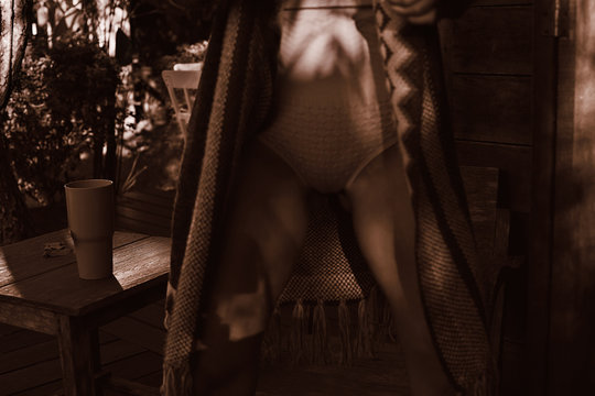 Human, beauty, art concept. Close up fragments of woman's body, drinking tea on wooden terrace. Sepia toned authentic artistic shot of cropped female taking a rest outdoors. Social networks content.