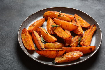 Baked, fried potato wedges with spices and rosemary. Roast potatoes with spices in the frying pan