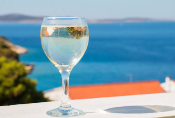 reflection of an island of greenery in a white wineglass against the blue sea