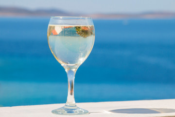 reflection of an island of greenery in a white wineglass against the blue sea
