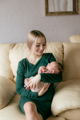 Obraz premium Young beautiful blond hair mamaso with a baby in her arms at home. Happy motherhood