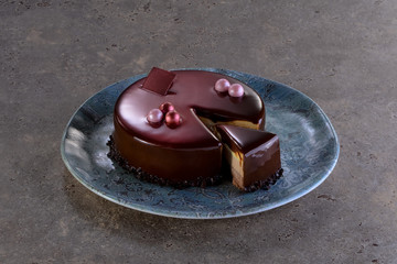 Torta ai 3 cioccolati con glassa lucida con porzione affettata