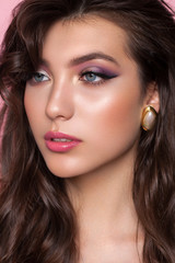 Close up portrait of a very beautiful brunette model with professional makeup, perfect skin and purple eyeshadows.