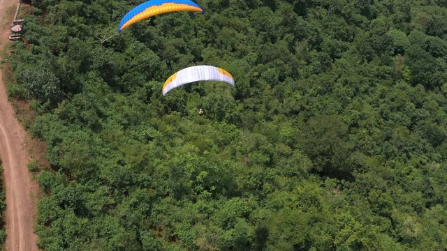 Amazing aerial video of flying paraglider on the background of wild nature. Paraplan drifting above the green tropical trees. Extreme sport. Hipster modern hobby concept. Paraplane flying in the sky.	