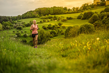 A middle-aged woman runs through the hills - 312177224