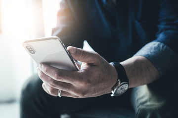 using cell phone.hand holding texting message on screen mobile chatting friend ,search internet information sitting on sofa in office.technology device contact communication connecting people concept