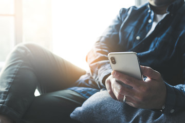 using cell phone.hand holding texting message on screen mobile chatting friend ,search internet information sitting on sofa in office.technology device contact communication connecting people concept