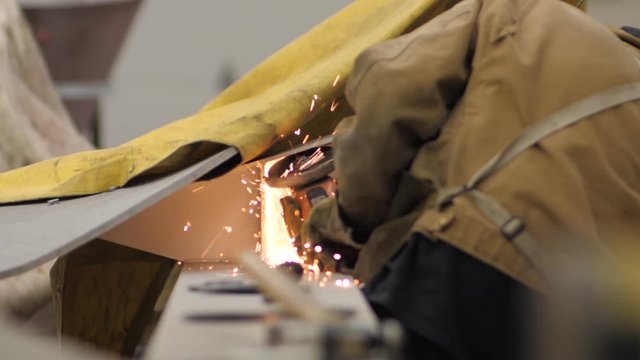 unrecognizable person sawing metal aluminum pieces in slow motion sparks flying